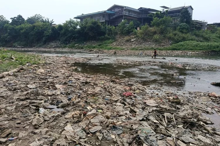 Kondisi debit air Kali Bekasi di Jalan Mayor Madmuin Hasibuan, Kelurahan Margahayu, Kecamatan Bekasi Timur, Selasa (22/7/2026), menyusut akibat musim kemarau. Surutnya air membuat dasar sungai dan tumpukan sampah yang sebelumnya tertutup aliran air terlihat di sejumlah titik bantaran sungai.