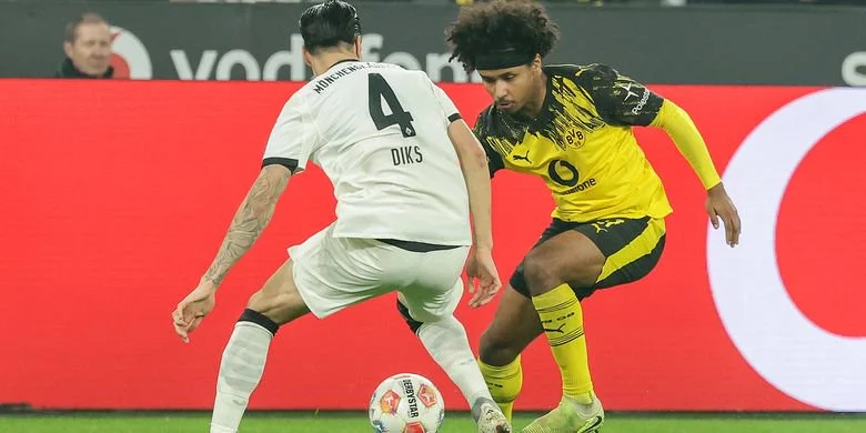 Karim Adeyemi (kanan) dari Borussia Dortmund berduel dengan Kevin Diks dari Borussia Moenchengladbach pada laga Bundesliga Borussia Dortmund dan Gladbach di Dortmund, Jerman, 19 Desember 2025.