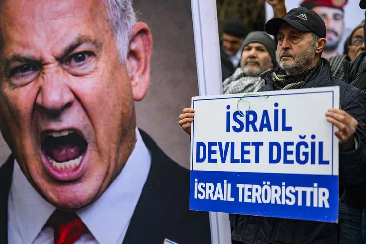 Pengunjuk rasa membawa poster bertuliskan, Israel bukan negara, Israel negara teroris, di samping poster Perdana Menteri Israel Benjamin Netanyahu, dalam demo anti-Amerika Serikat di depan Konsulat AS di Istanbul, Turkiye, 1 Februari 2026.
