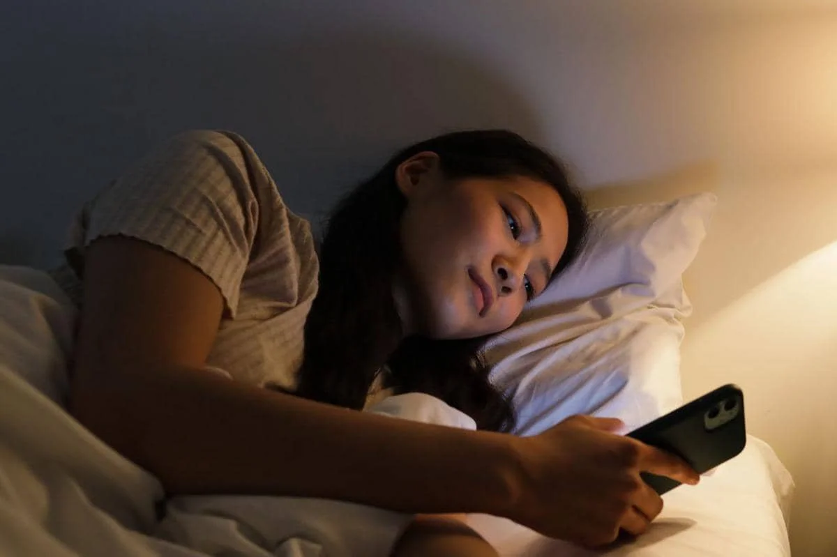 ilustrasi wanita bermain ponsel pada malam hari sebelum tidur