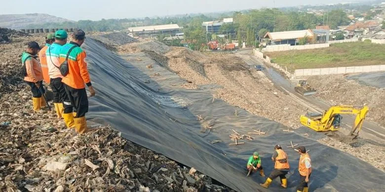 Nampak para petugas sedang menutupin tumpukan sampah di TPST Bantargebang dengan material khusus. 