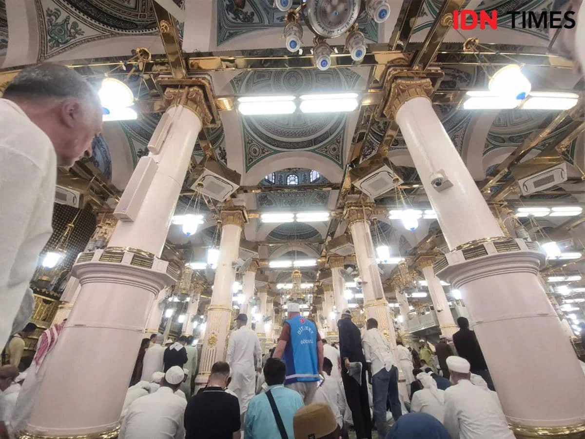 Jemaah berpakaian putih memenuhi area Raudah dengan pilar berornamen emas dan lampu gantung megah di Masjid Nabawi.