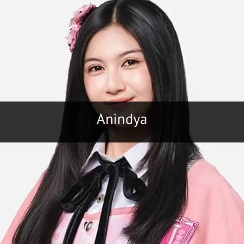 Seorang perempuan berambut panjang mengenakan seragam berwarna merah muda dengan pita hitam dan aksesori bunga di rambutnya.