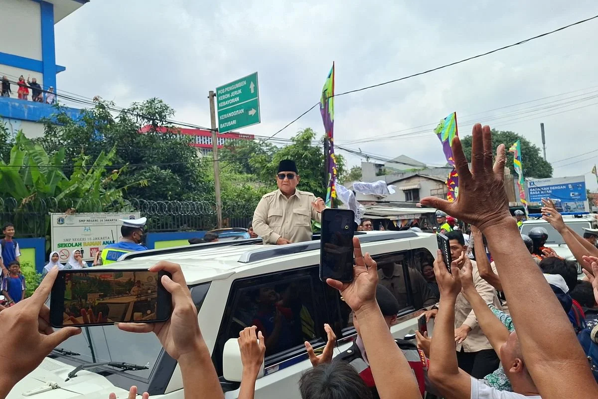 Presiden RI Prabowo Subianto melempar kaos kepada kerumunan warga di Jalan Palmerah Barat, Palmerah, Jakarta Barat, Jumat (13/2/2026) siang