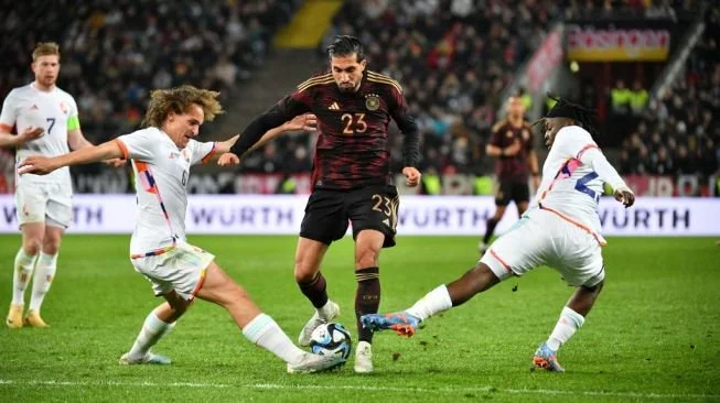 Gelandang timnas Jerman Emre Can (tengah) dihadang oleh bek Belgia Wout Faes dan gelandang Johan Bakayoko (kanan) selama pertandingan persahabatanantara Jerman vs Belgia di Stadion RheinEnergie, Koln, pada 28 Maret 2023.UWE KRAFT / AFP