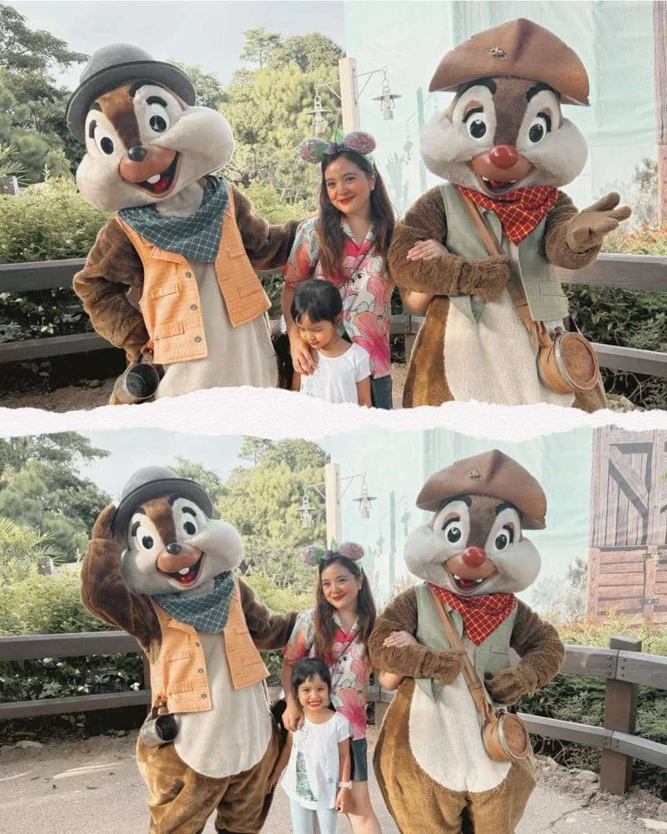 Seorang wanita dan anak kecil berpose bersama dua karakter Chip dan Dale di Disneyland Hong Kong dengan latar taman hijau.