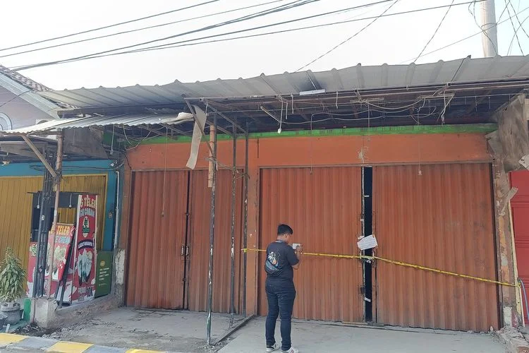 Ruko bercat oranye di Perumahan Puri Cendana, Tambun Selatan, Kabupaten Bekasi, yang diduga menjadi lokasi penambangan Bitcoin, dipasangi garis polisi, dirantai, dan digembok setelah disegel aparat. Jumat (3/7/2026).