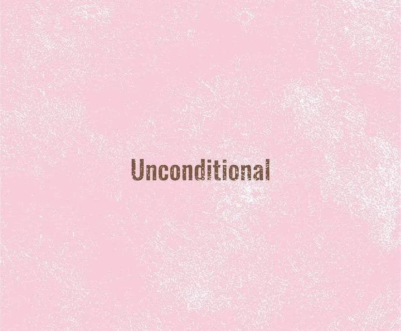 Teks kata 'Unconditional' berwarna cokelat di tengah latar bertekstur warna merah muda lembut dengan nuansa minimalis.