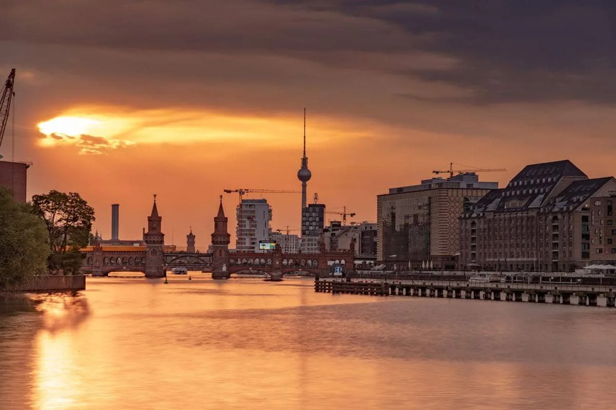Pemandangan matahari terbenam yang memukau di Berlin, Jerman, yang juga menampilkan Jembatan Oberbaum yang membentang di atas Sungai Spree.