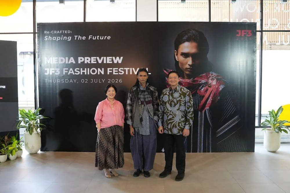 Tiga orang berpose di depan backdrop bertuliskan Media Preview JF3 Fashion Festival 2026 dengan tema Re-Crafted: Shaping The Future.