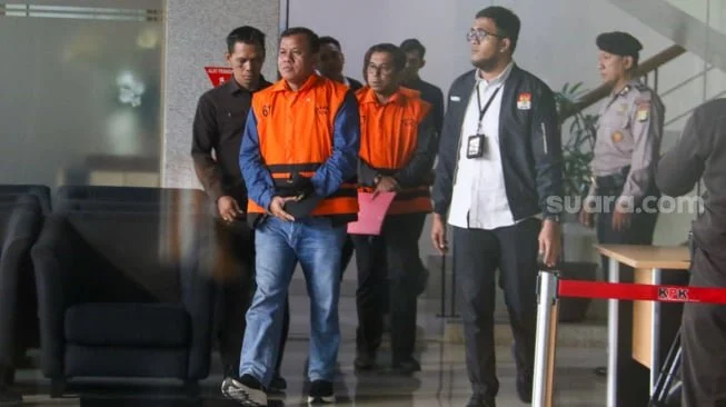 Bupati Kuantan Singingi Suhardiman Amby (tengah) berjalan menuju mobil tahanan usai menjalani pemeriksaan di Gedung Merah Putih KPK, Jakarta, Rabu (1/7/2026). [Suara.com/Alfian Winanto]