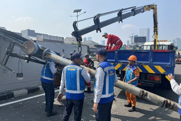 Foto: Petugas tengah sibuk mengevakuasi plang atau tiang rambu jalan yang roboh usai terhantam mobil dinas TNI di Tol Dalam Kota, tepatnya di depan Gedung DPR/MPR RI, Jakarta Pusat, Kamis (9/7/2026).