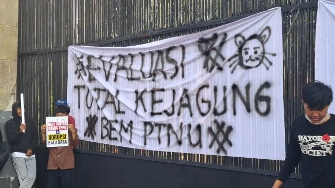 Spanduk putih bertuliskan "Evaluasi Total Kejangung" membentang pagar Gedung DPR/MPR, Senayan, Jakarta, Jumat petang (10/7/2026). [Suara.com/Cornelius Juan Prawira]