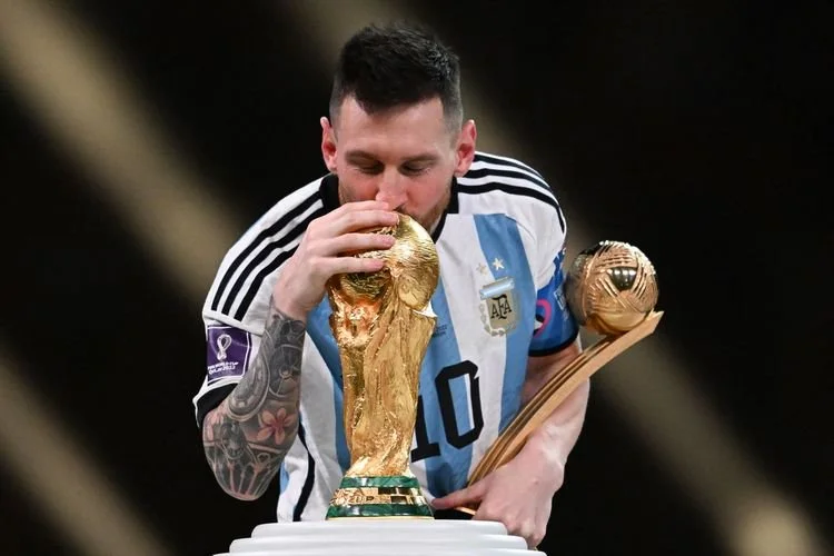 Kapten Argentina Lionel Messi mencium Trofi Piala Dunia FIFA setelah memenangi pertandingan final Piala Dunia 2022 Qatar antara Argentina vs Perancis di Stadion Lusail di Lusail, utara Doha pada Minggu 18 Desember 2022. Keberhasilan Lionel Messi melengkapi koleksi gelarnya dengan trofi Piala Dunia membuat Ronaldinho ikut bahagia. 