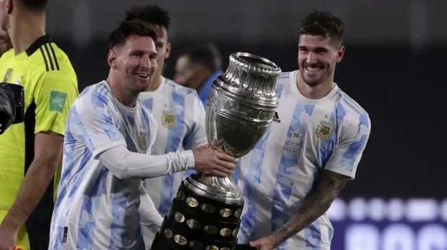 Penyerang timnas Argentina Lionel Messi (kiri) dan gelandang Rodrigo De Paul (kanan) memegang trofi Copa America sambil berpose untuk foto setelah akhir pertandingan sepak bola kualifikasi Piala Dunia 2022 zona Amerika Selatan kontra Bolivia di Stadion El Monumental di Buenos Aires pada 9 September 2021.Juan Ignacio RONCORONI / POOL / AFP