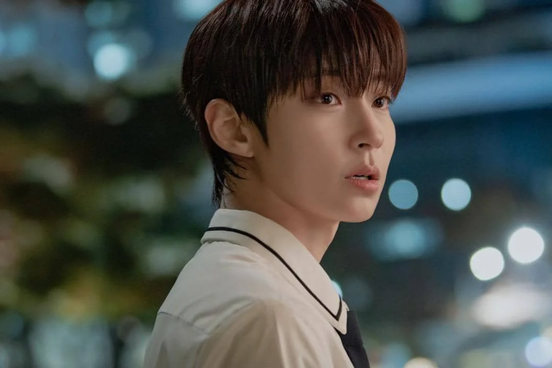 Seorang pria muda mengenakan seragam sekolah dengan latar malam bercahaya dalam adegan drama Dream to You.