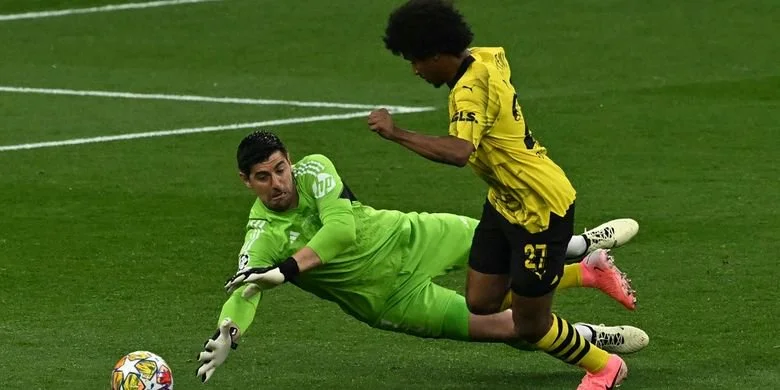 Kiper Real Madrid, Thibuat Courtois, saat menggagalkan tendangan penyerang Borussia Dortmund, Karim Adeyemi, dalam laga final Liga Champions 2023-2024. Duel Borussia Dortmund vs Real Madrid digelar di Stadion Wembley, London, Inggris, Minggu (2/6/2024) dini hari WIB. (Photo by Ben Stansall / AFP)
