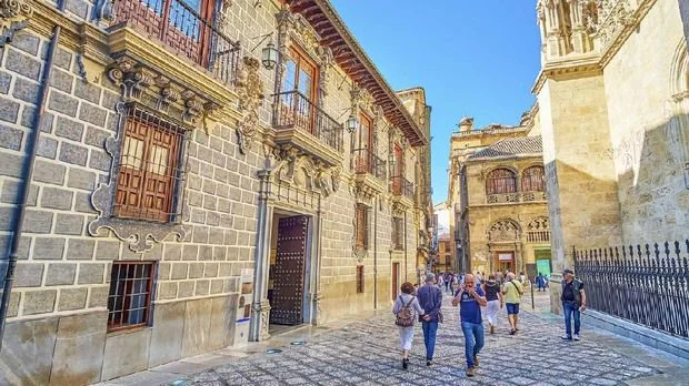 Granada, Spain - September 25, 2019: Tourists walk in Calle Oficios (La Lonja square), lined with historic buildings of Capilla Real (Royal Chapel) and Palacio de la Madraza (Madrasah school)