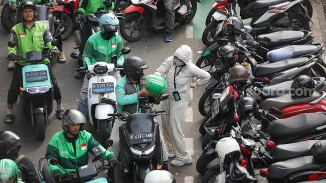 Pengemudi ojek online menjemput penumpang di seberang Stasiun Palmerah, Jakarta, Kamis (2/7/2026). [Suara.com/Alfian Winanto]